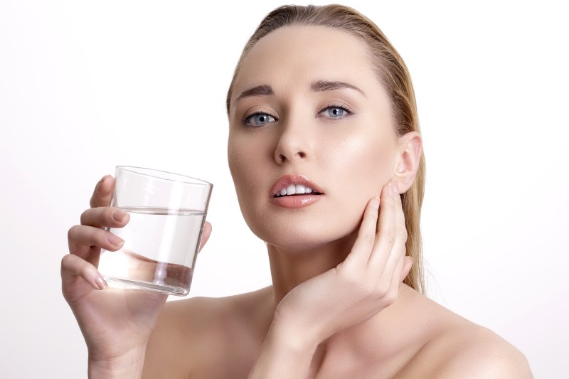 beautiful young beautiful woman drinking fresh water on white