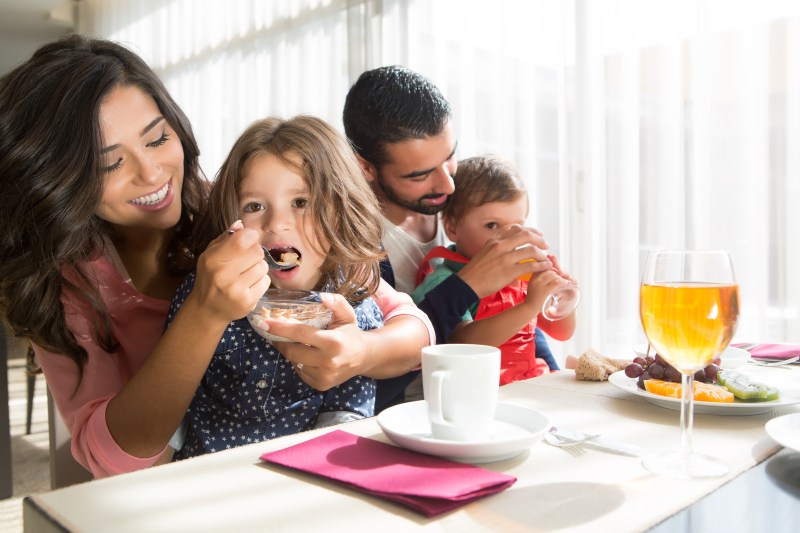 Young latin family having breakfast with kids
