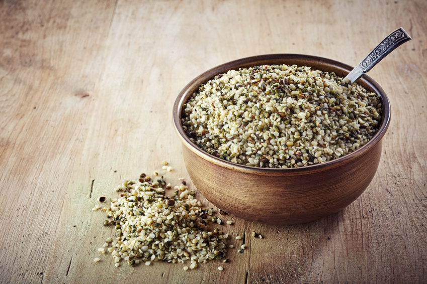 Bowl of shelled hemp seeds on wooden background