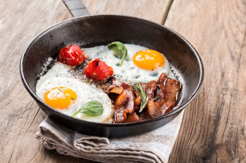 Fried eggs with bacon and tomato in a pan