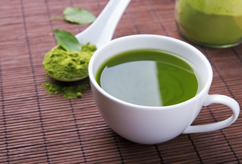 Green tea matcha in a white cup on the brown mat close-up