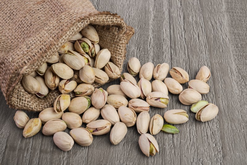 Pistachios nuts in burlap sack on vintage wooden table