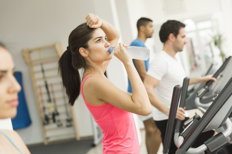 Woman training and drinking water in the gym